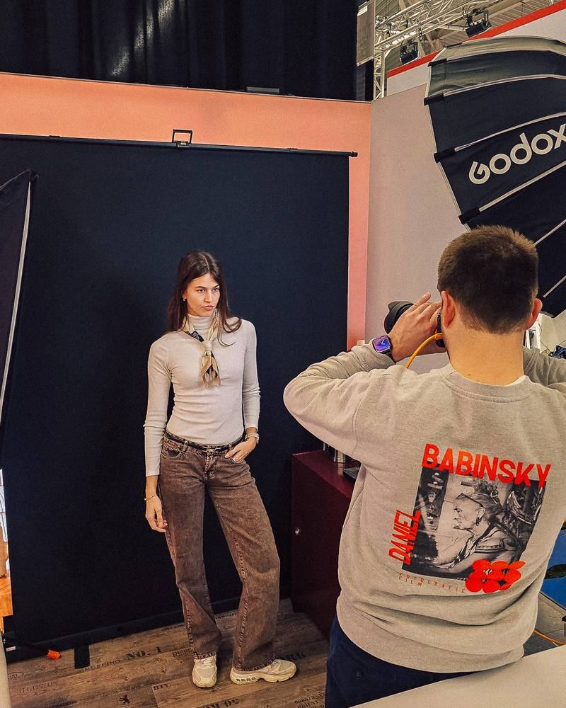 Daniel Babinsky fotografiert eine Frau vor einem Hintergrund am Set