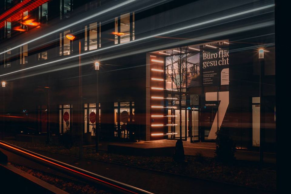 Gewerbeobjekt bei Nacht mit Leuchtschrift Büroflächen gesucht und Lichtspuren