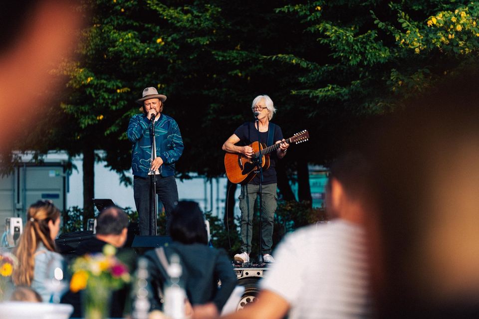 Firmenevent der Rocholl GmbH: zwei Musiker auf einer Bühne im Freien, Gäste im Vordergrund