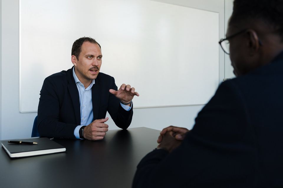Berater von grynia consulting erklärt im Gespräch am Tisch, Gegenüber im Anschnitt