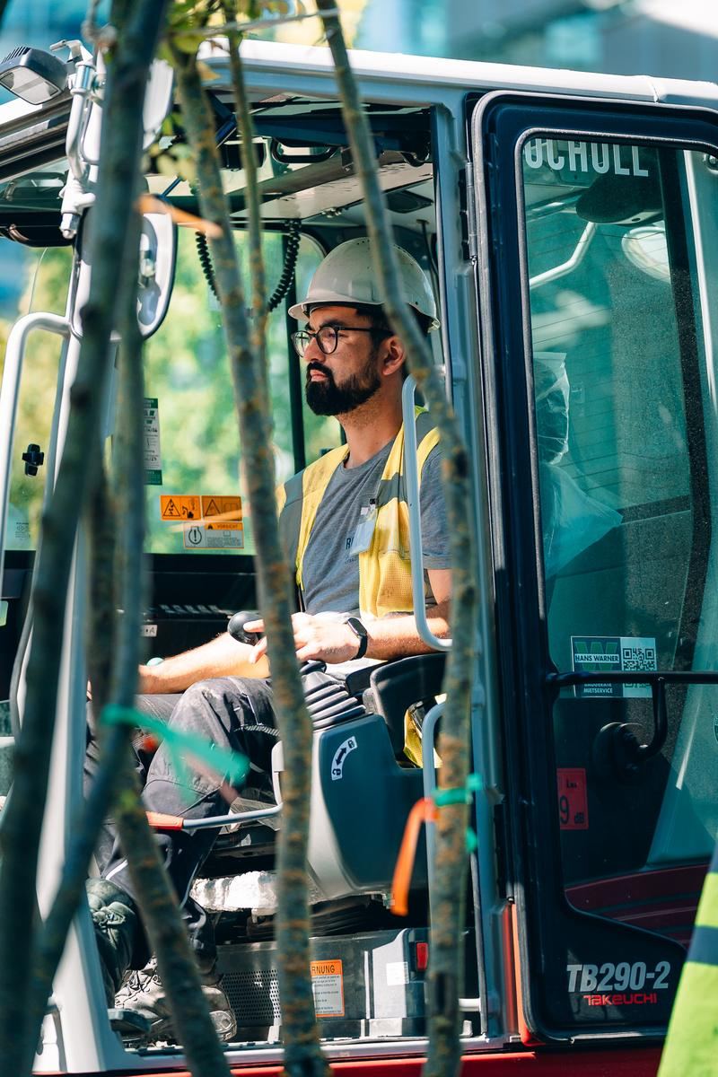 Baggerfahrer in der Kabine auf einer Baustelle, Blick zur Seite