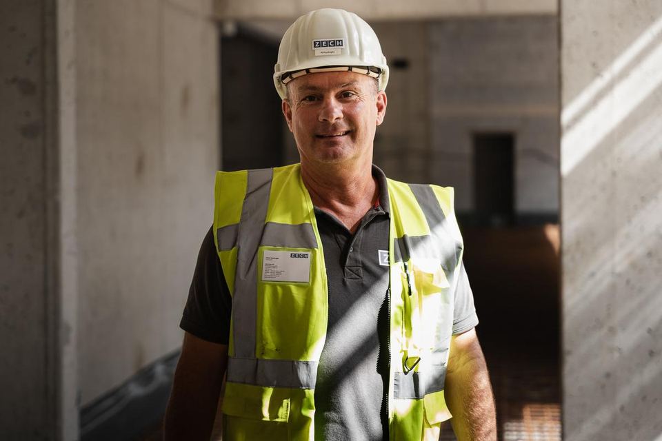 Bauleiter mit Helm und Warnweste im Rohbau, Portrait