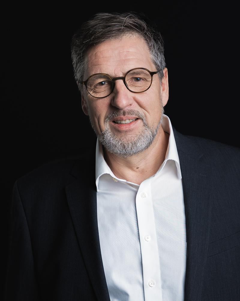 Mitarbeiterportrait eines Mannes mit Brille und Jackett